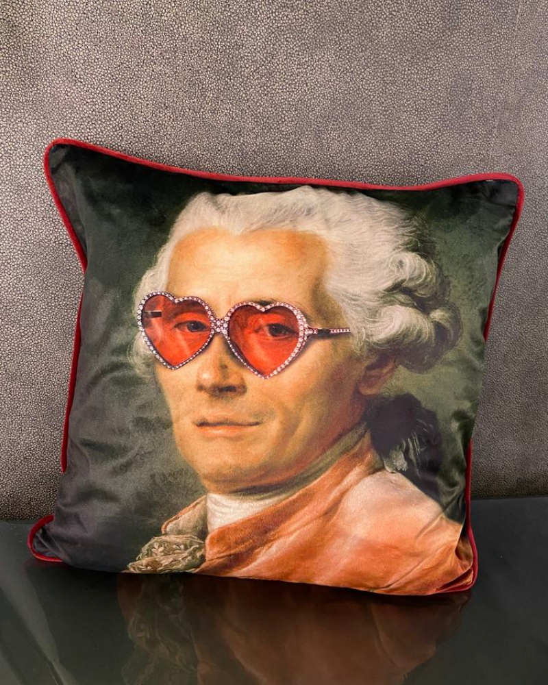 Un coussin carré avec l'imprimé d'un portrait de marquis portant des lunettes rouges est un cadeau de Noël original.