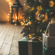 Cadeaux de Noël posés sur du parquet au pied d'un sapin de Noël illuminé